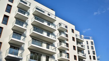 Gündüz gözüyle modern yerleşim yerinin dış tarafında. Mavi gökyüzü olan güneşli bir günde modern apartman binaları. Modern bir apartmanın cephesi