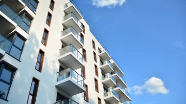 Gündüz gözüyle modern yerleşim yerinin dış tarafında. Mavi gökyüzü olan güneşli bir günde modern apartman binaları. Modern bir apartmanın cephesi