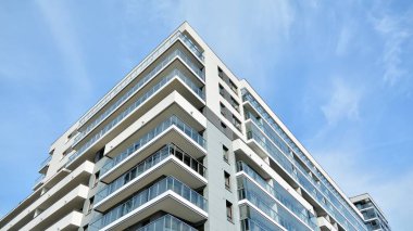 Gündüz gözüyle modern yerleşim yerinin dış tarafında. Mavi gökyüzü olan güneşli bir günde modern apartman binaları. Modern bir apartmanın cephesi