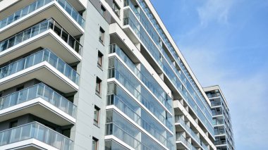 Gündüz gözüyle modern yerleşim yerinin dış tarafında. Mavi gökyüzü olan güneşli bir günde modern apartman binaları. Modern bir apartmanın cephesi