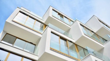 Gündüz gözüyle modern yerleşim yerinin dış tarafında. Mavi gökyüzü olan güneşli bir günde modern apartman binaları. Modern bir apartmanın cephesi