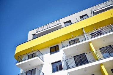 Mavi gökyüzü olan güneşli bir günde modern apartman binaları. Modern bir apartmanın cephesi