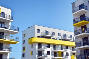 Mavi gökyüzü olan güneşli bir günde modern apartman binaları. Modern bir apartmanın cephesi