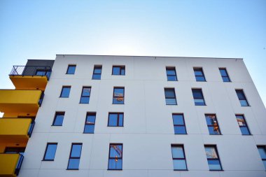 Mavi gökyüzü olan güneşli bir günde modern apartman binaları. Modern bir apartmanın cephesi