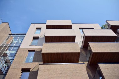 Mavi gökyüzü olan güneşli bir günde modern apartman binaları. Modern bir apartmanın cephesi