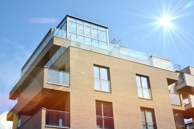 Mavi gökyüzü olan güneşli bir günde modern apartman binaları. Modern bir apartmanın ön cephesi. Güneş ışığıyla kaplı cam yüzey..