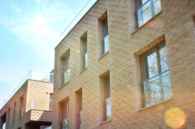 Mavi gökyüzü olan güneşli bir günde modern apartman binaları. Modern bir apartmanın ön cephesi. Güneş ışığıyla kaplı cam yüzey..