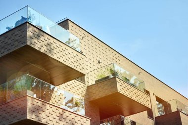 Mavi gökyüzü olan güneşli bir günde modern apartman binaları. Modern bir apartmanın ön cephesi. Güneş ışığıyla kaplı cam yüzey..