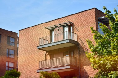 Mavi gökyüzü olan güneşli bir günde modern apartman binaları. Modern bir apartmanın ön cephesi. Güneş ışığıyla kaplı cam yüzey..