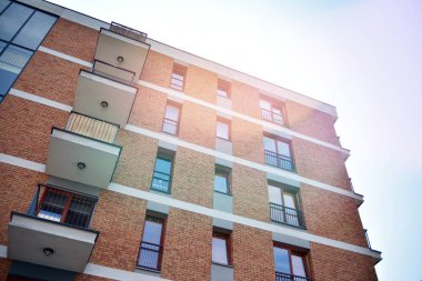 Mavi gökyüzü olan güneşli bir günde modern apartman binaları. Modern bir apartmanın ön cephesi. Güneş ışığıyla kaplı cam yüzey..