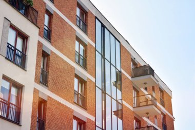 Mavi gökyüzü olan güneşli bir günde modern apartman binaları. Modern bir apartmanın ön cephesi. Güneş ışığıyla kaplı cam yüzey..