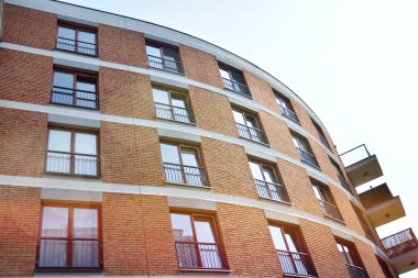 Mavi gökyüzü olan güneşli bir günde modern apartman binaları. Modern bir apartmanın ön cephesi. Güneş ışığıyla kaplı cam yüzey..