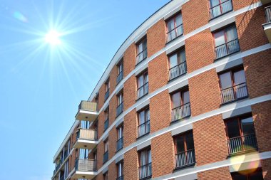 Mavi gökyüzü olan güneşli bir günde modern apartman binaları. Modern bir apartmanın ön cephesi. Güneş ışığıyla kaplı cam yüzey..