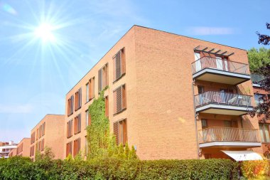 Mavi gökyüzü olan güneşli bir günde modern apartman binaları. Modern bir apartmanın ön cephesi. Güneş ışığıyla kaplı cam yüzey..