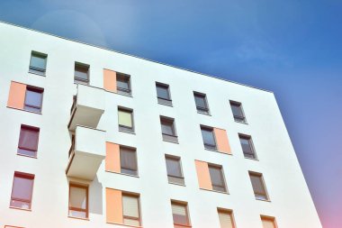 Mavi gökyüzü olan güneşli bir günde modern apartman binaları. Modern bir apartmanın ön cephesi. Güneş ışığıyla kaplı cam yüzey..