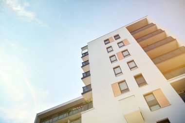 Mavi gökyüzü olan güneşli bir günde modern apartman binaları. Modern bir apartmanın ön cephesi. Güneş ışığıyla kaplı cam yüzey..