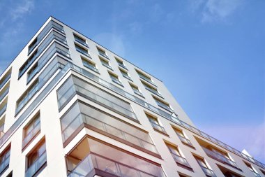 Mavi gökyüzü olan güneşli bir günde modern apartman binaları. Modern bir apartmanın ön cephesi. Güneş ışığıyla kaplı cam yüzey..