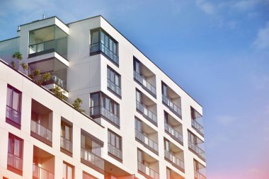 Mavi gökyüzü olan güneşli bir günde modern apartman binaları. Modern bir apartmanın ön cephesi. Güneş ışığıyla kaplı cam yüzey..