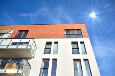 Mavi gökyüzü olan güneşli bir günde modern apartman binaları. Modern bir apartmanın ön cephesi. Güneş ışığıyla kaplı cam yüzey..