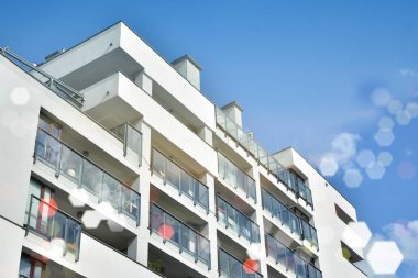 Mavi gökyüzü olan güneşli bir günde modern apartman binaları. Modern bir apartmanın ön cephesi. Güneş ışığıyla kaplı cam yüzey..