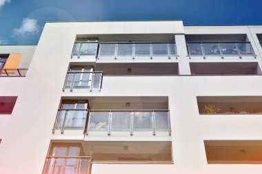 Mavi gökyüzü olan güneşli bir günde modern apartman binaları. Modern bir apartmanın ön cephesi. Güneş ışığıyla kaplı cam yüzey..