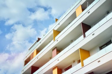 Mavi gökyüzü olan güneşli bir günde modern apartman binaları. Modern bir apartmanın ön cephesi. Güneş ışığıyla kaplı cam yüzey..