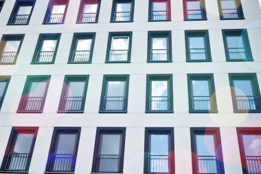 Mavi gökyüzü olan güneşli bir günde modern apartman binaları. Modern bir apartmanın ön cephesi. Güneş ışığıyla kaplı cam yüzey..