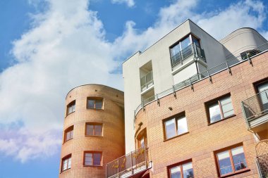 Mavi gökyüzü olan güneşli bir günde modern apartman binaları. Modern bir apartmanın ön cephesi. Güneş ışığıyla kaplı cam yüzey..