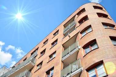 Mavi gökyüzü olan güneşli bir günde modern apartman binaları. Modern bir apartmanın ön cephesi. Güneş ışığıyla kaplı cam yüzey..