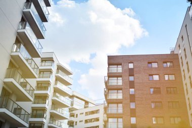 Mavi gökyüzü olan güneşli bir günde modern apartman binaları. Modern bir apartmanın ön cephesi. Güneş ışığıyla kaplı cam yüzey..