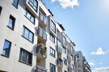 Mavi gökyüzü olan güneşli bir günde modern apartman binaları. Modern bir apartmanın cephesi