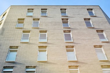 Mavi gökyüzü olan güneşli bir günde modern apartman binaları. Modern bir apartmanın ön cephesi. Güneş ışığıyla kaplı cam yüzey..