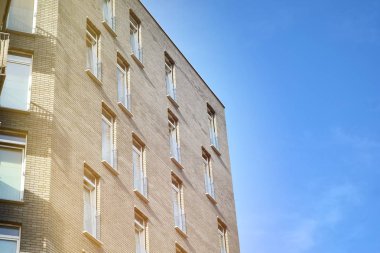 Mavi gökyüzü olan güneşli bir günde modern apartman binaları. Modern bir apartmanın ön cephesi. Güneş ışığıyla kaplı cam yüzey..
