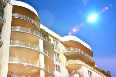 Mavi gökyüzü olan güneşli bir günde modern apartman binaları. Modern bir apartmanın ön cephesi. Güneş ışığıyla kaplı cam yüzey..