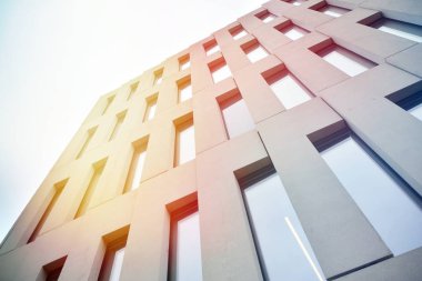 Modern ofis binası detayı. Güneş ışığı ile modernist brutalist tarzı bina yüzeyinin cephesinde geometrik açısal beton pencerelerperspektif görünümü.