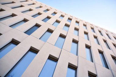 Modern ofis binası detayı. Modernist brutalist tarzı binanın cephesinde geometrik açısal beton pencerelerin perspektif görünümü. 