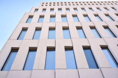 Modern ofis binası detayı. Modernist brutalist tarzı binanın cephesinde geometrik açısal beton pencerelerin perspektif görünümü. 