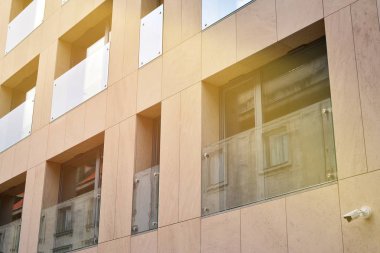 Mavi gökyüzü olan güneşli bir günde modern apartman binaları. Modern bir apartmanın ön cephesi. Güneş ışığıyla kaplı cam yüzey..