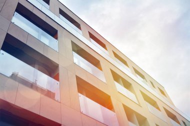 Mavi gökyüzü olan güneşli bir günde modern apartman binaları. Modern bir apartmanın ön cephesi. Güneş ışığıyla kaplı cam yüzey..