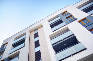 Mavi gökyüzü olan güneşli bir günde modern apartman binaları. Modern bir apartmanın cephesi