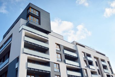 Mavi gökyüzü olan güneşli bir günde modern apartman binaları. Modern bir apartmanın cephesi