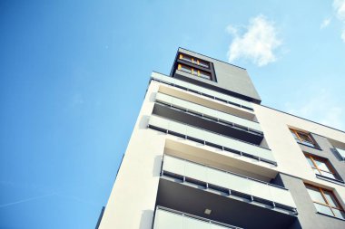Mavi gökyüzü olan güneşli bir günde modern apartman binaları. Modern bir apartmanın cephesi