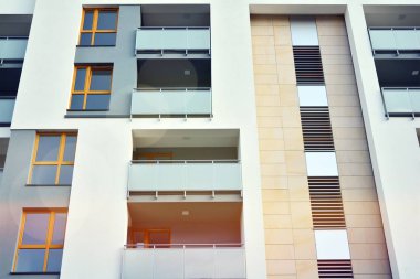 Mavi gökyüzü olan güneşli bir günde modern apartman binaları. Modern bir apartmanın ön cephesi. Güneş ışığıyla kaplı cam yüzey..