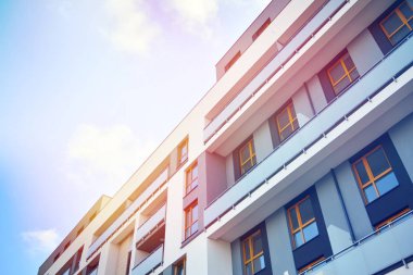 Mavi gökyüzü olan güneşli bir günde modern apartman binaları. Modern bir apartmanın ön cephesi. Güneş ışığıyla kaplı cam yüzey..