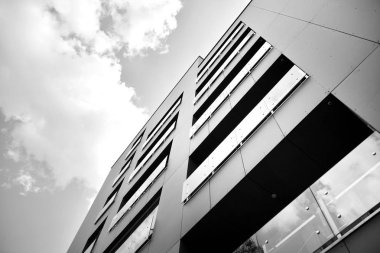 Pencereleri ve balkonları olan bir binanın ön cephesi. Birçok dairesi olan modern bir ev. Siyah ve beyaz.