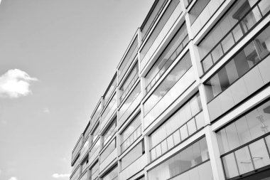 Pencereleri ve balkonları olan bir binanın ön cephesi. Birçok dairesi olan modern bir ev. Siyah ve beyaz.