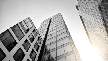 Çelik ve camdan yapılmış, mavi gökyüzü olan modern ofis duvarı. Güneş ışığıyla cam yüzey. Siyah ve beyaz.