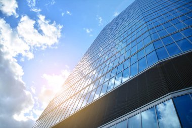 Cam aynalı ofis binasının ön dokusu. Ön cephenin bir parçası. Günbatımında akşam ışığında mercek filtre efektiyle modern gökdelenlerin en alt görüntüsü.