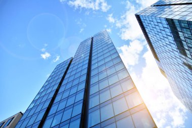 Cam aynalı ofis binasının ön dokusu. Ön cephenin bir parçası. Günbatımında akşam ışığında mercek filtre efektiyle modern gökdelenlerin en alt görüntüsü.