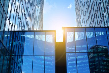 Cam aynalı ofis binasının ön dokusu. Ön cephenin bir parçası. Günbatımında akşam ışığında mercek filtre efektiyle modern gökdelenlerin en alt görüntüsü.